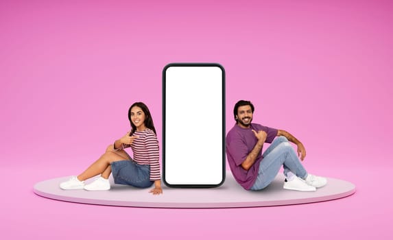 Relaxed indian lovers chilling on platform next to huge phone