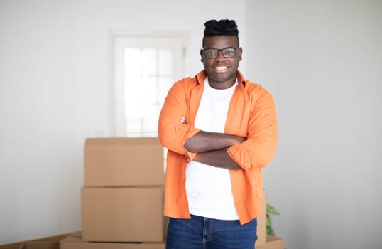 Relocation Concept. Handsome Young Black Man Posing In Room With Cardboard Boxes