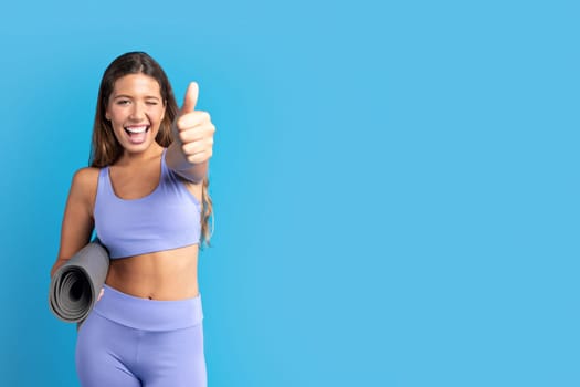 Happy glad millennial european lady in sportswear with mat show thumb up, approval pilates