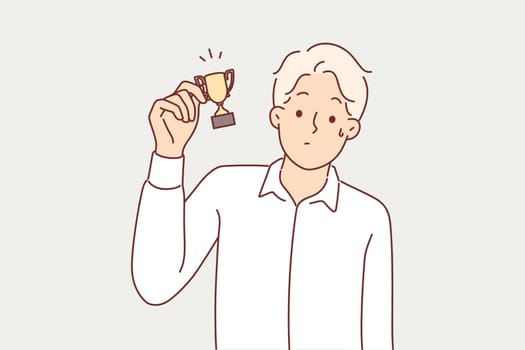 Man with small cup for minor achievement feels displaced after receiving consolation prize