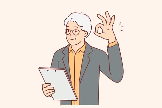Elderly businessman showing OK gesture and holding clipboard checking work of subordinates