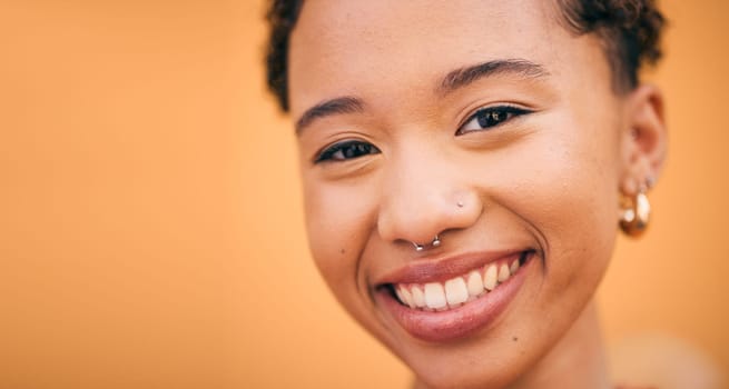 Happy, woman and face closeup in studio with smile and confidence feeling cute. Orange background, young portrait and African female person with trendy, piercing and student fashion with gen z glow
