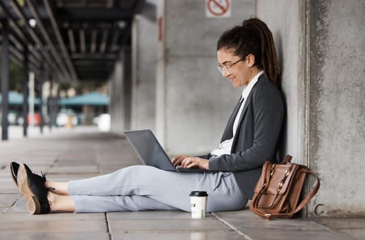 Laptop, typing and woman on a coffee break in the city or employee relax on social media, internet or online connection. Remote, virtual work and digital nomad or person sitting on computer on street