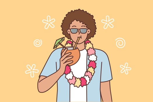 Ethnic man tourist from island of Hawaii drinks coconut cocktail and invites to beach party