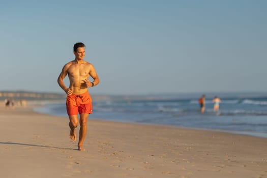 An attractive man with nice athletic body jogging on the shore