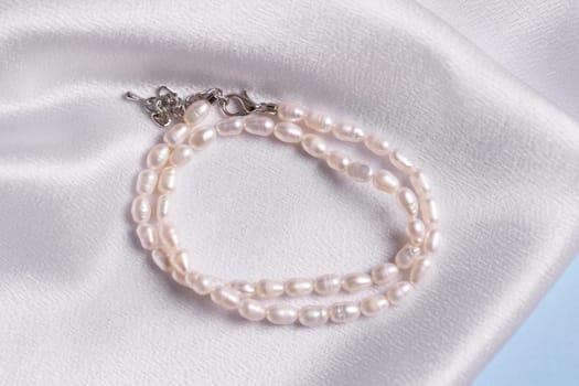 Elegance pearl bracelet on silk fabric background. Jewellery and handmade accessories concept