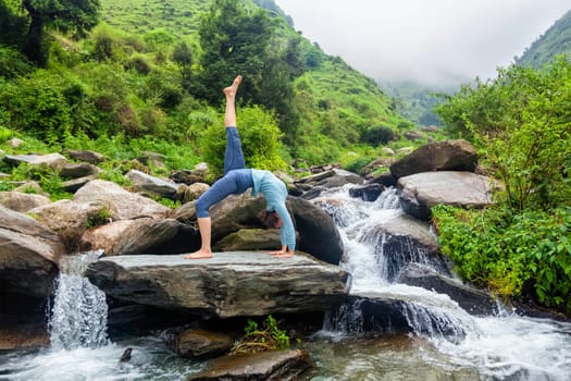 Woman doing yoga asana at waterfall