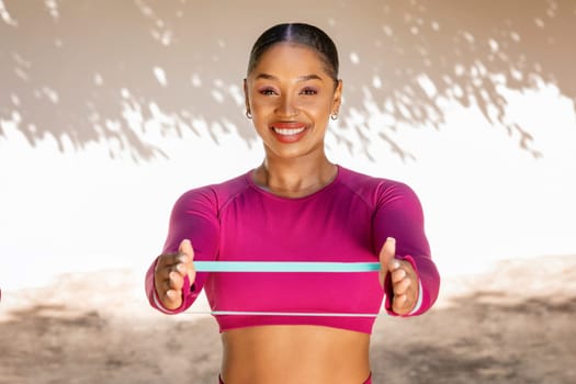 Athletic african american sportswoman exercising with stretch band outdoor
