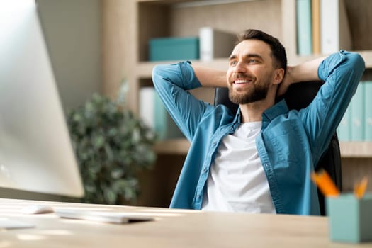 Portrait Of Smiling Millennial Male Entrepreneur Relaxing At Workplace In Office