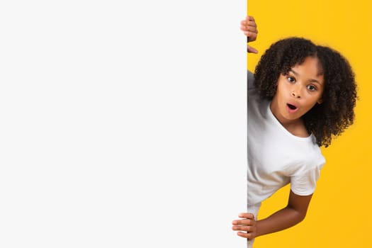 Shocked positive teenage black pupil girl in white t-shirt near banner with copy space