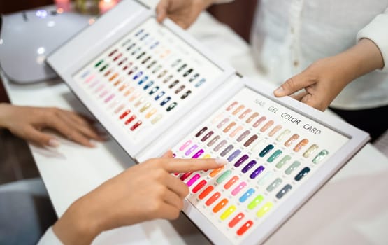 Closeup of Client Lady Choosing Nail Color With Manicurist Indoor