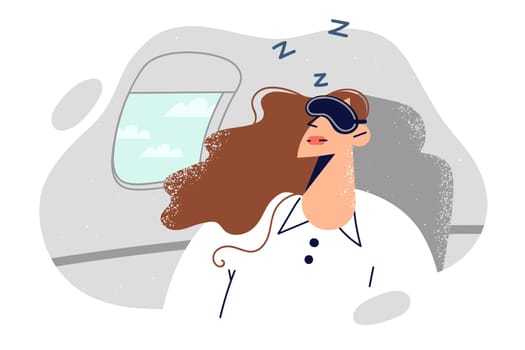 Woman passenger on airplane sleeps with mask over eyes, going on business trip.