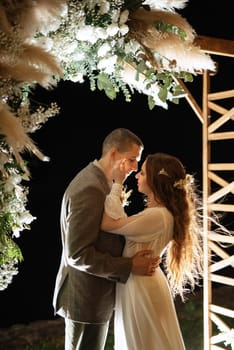 bride and groom against the backdrop of an evening wedding arch