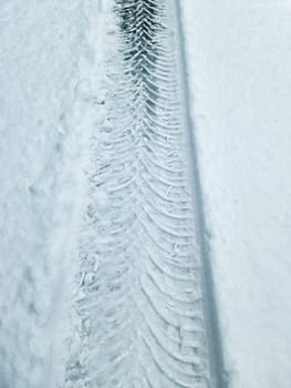 Tire Tracks on snow covered streets in a close up view.