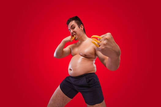 A funny fat man isolated on red background. Obesity and eating disorder. Concept for dietetics and fitness advertising in social networks.