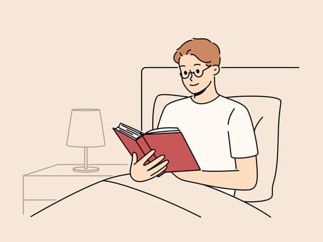 Man reads book before bedtime, sitting in bed at night and enjoying plot of fantasy novel