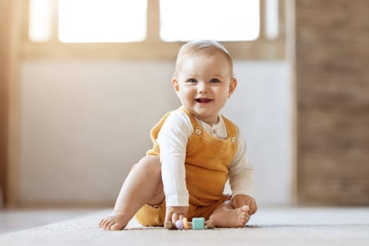 Adorable blonde infant baby playing with kids toys at home