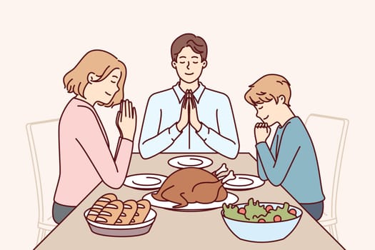 Family pray before dinner, sitting at table with delicious food and thank god for well-being
