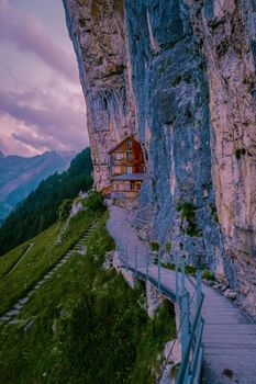 Swiss Alps and a mountain restaurant under the Aescher cliff viewed from mountain Ebenalp in the Appenzell region in Switzerland Aescher cliff
