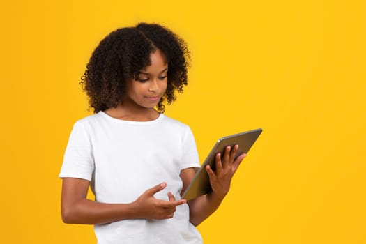 Smiling adolescent african american girl in white t-shirt, use tablet to chat in social networks