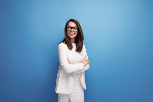 charming brunette woman in white dress on blue studio background