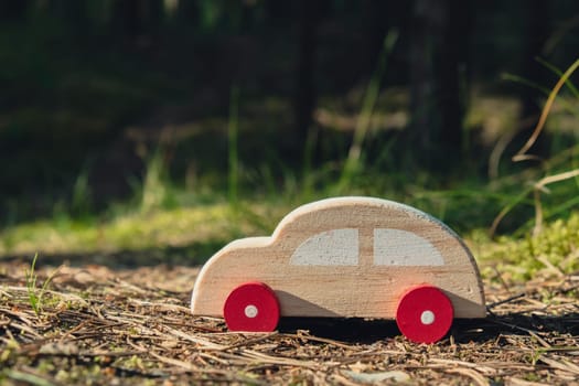 Wooden toy car on greenery forest background. Eco-car concept World car free day electric vehicle environment automobile transportation electric vehicle. Hybrid electric. Sustainable engine. Zero CO2 emission for natural awareness