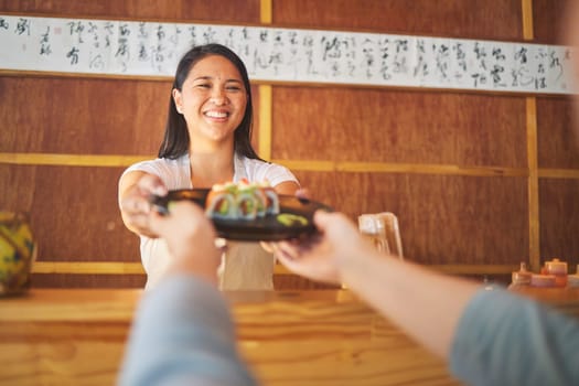 Sushi, restaurant worker job and woman with smile from food and Asian meal in a kitchen. Happy, female waiter or chef working with salmon roll lunch order with cooking in Japanese bar with service