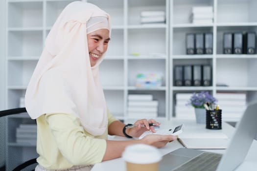 Muslim women use calculators, computers, and laptops to check their accounts at work.