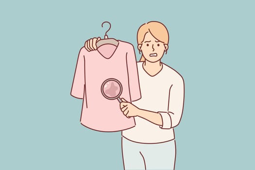 Woman shows stain on t-shirt under magnifying glass and needs to use laundry detergent
