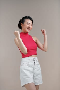 Emotional asian girl expressing amazement over beige studio background