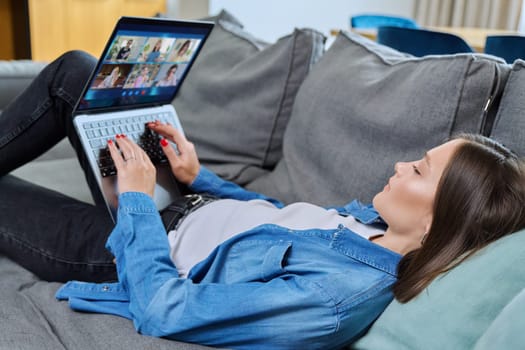 Young female having video conference with group of teenage students on laptop