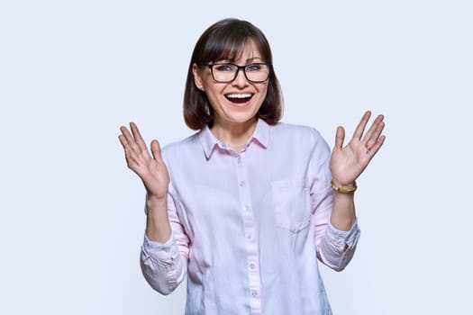 Happy emotional middle aged woman looking at camera on light background