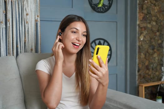 Hispanic girl answers a video call on her smartphone in her apartment. Attractive Latin woman doing a video conference at home.