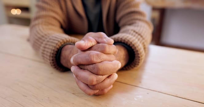 Hands together, person and stress with table and problem from despair and praying. Anxiety, hope and issue in a retirement home with grief, religion and challenge at a house with worry or gratitude