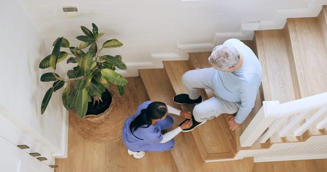 Nurse tie shoes of senior man on stairs at home, help and top view of support. Caregiver tying sneakers of elderly person from above, assistance and health, medical worker and woman on steps in house