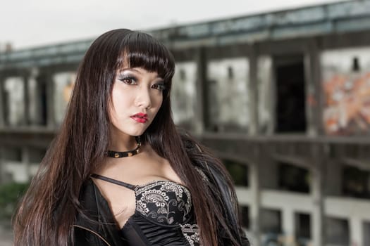 Asian woman in emo goth clothes at an abandoned building