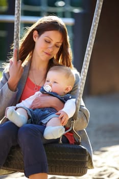 Woman, baby and swing on park for play, bonding and love with sunshine, child development and care. Mother, kid and infant swinging outdoor in summer for fun, enjoyment and nurture with happiness