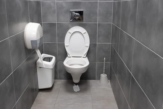 White toilet and trash can in a gray restroom