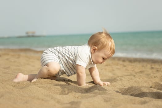 A baby boy crawling on a sand on the seaside