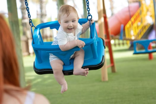 A little funny boy on swings on an outside playground