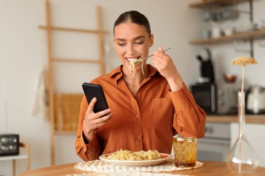 Woman eating noodles while checking her smartphone