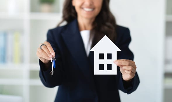 Real estate agent holding home key and model of house