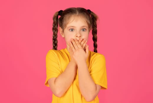 Portrait of shocked little girl covering her mouth with hands