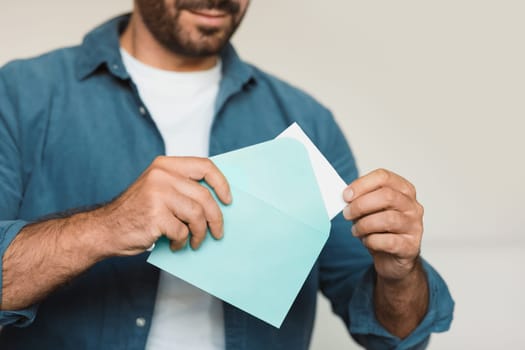 Unrecognizable middle aged man opening envelope receiving a letter indoor