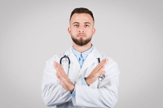 Doctor man with crossed arms making stopping gesture