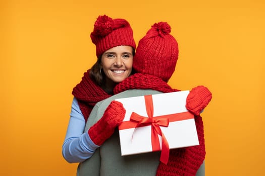 Cheerful senior european wife in hat hug husband at winter, gift box present