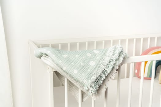 Muslin baby blanket hanging on child's bed in nursing room
