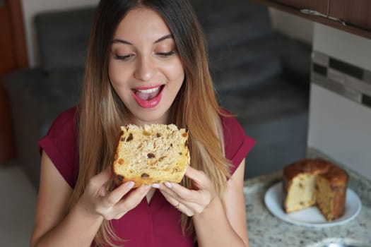 Close up of Brazilian girl eating a slice of Panettone traditional Christamas cake with raisins and candied fruits at home