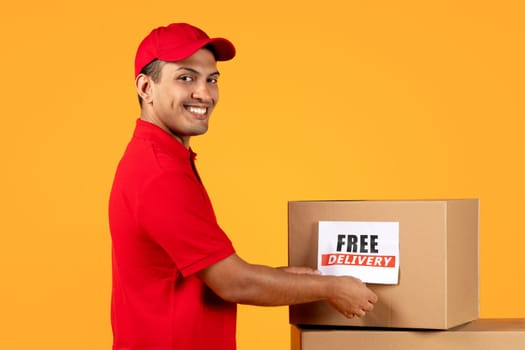 courier man holds parcel box with Free Delivery label, studio