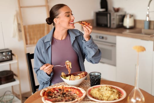 Pregnant lady enjoys pizza and pasta in a homely kitchen